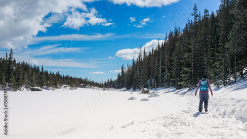 A female hiker hikes in the forest and mountains with snow in winter.