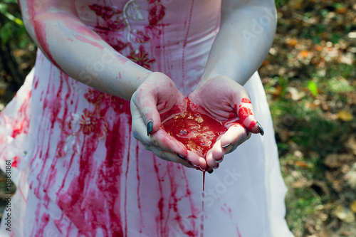 Hands of a girl in white dressed together full of red blood