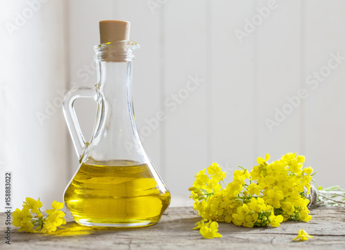 rapeseed oil (canola) and rape flowers on wooden table