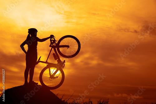 Silhouettes of biker-girl at the sunset