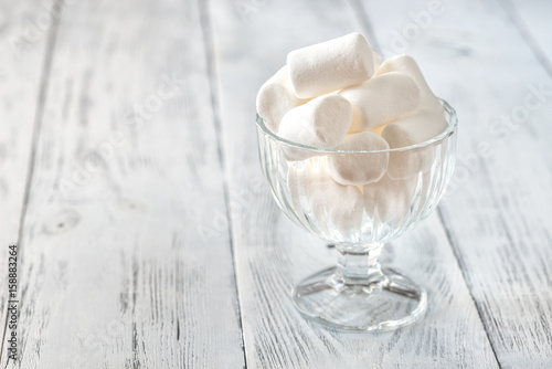 Glass bowl of marshmallows on the wooden background