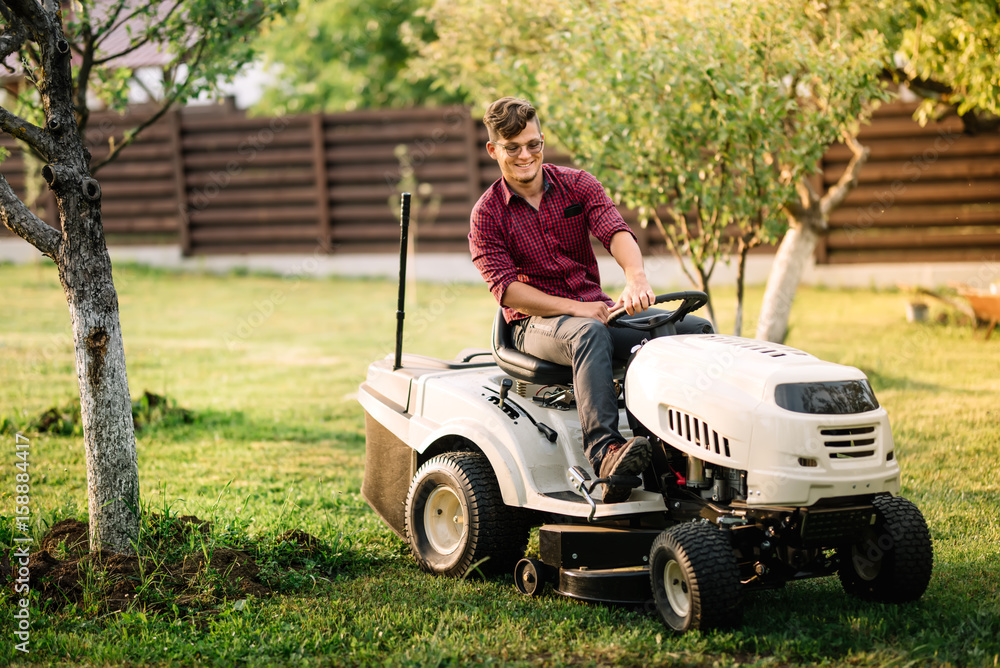 Fototapeta premium male worker using lawmower for landscaping works. Motorised agriculture concept