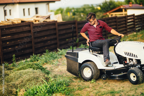 Man with lawn mower, professional worker cutting and unloading grass © aboutmomentsimages