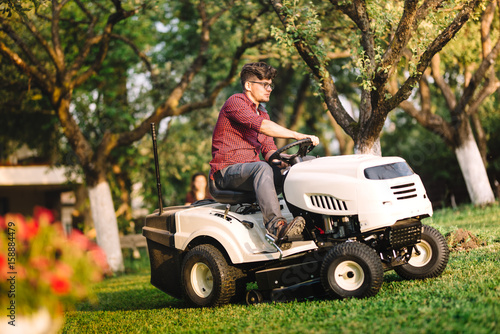 Professional gardner using lawn mower and cutting grass © aboutmomentsimages
