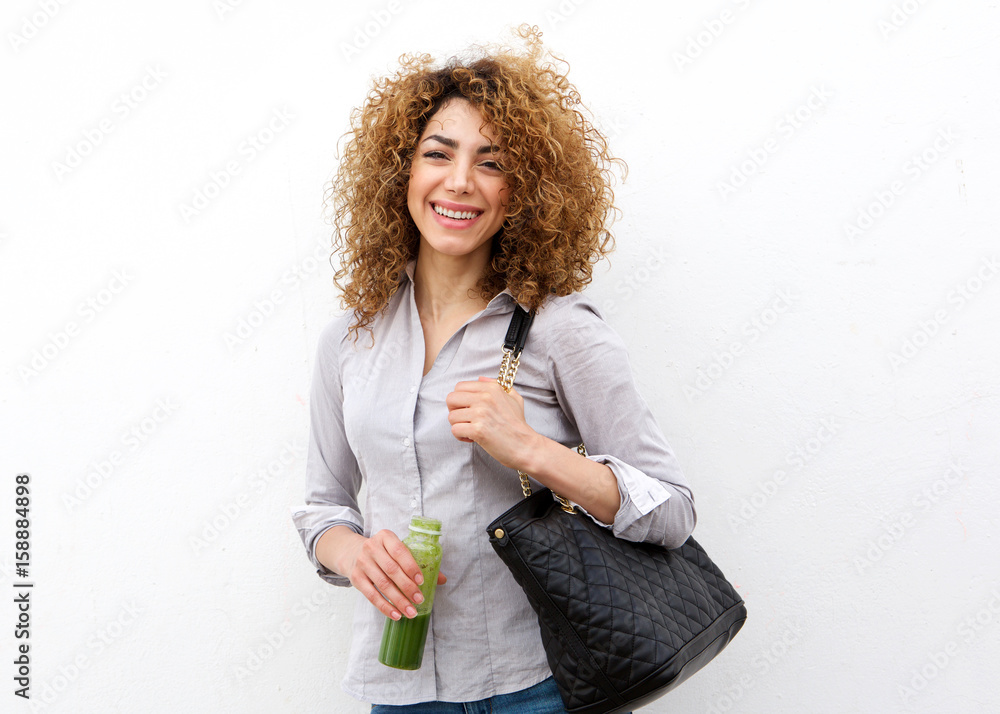 Happy young woman holding juice drink by white wall Happy young woman holding juice drink by white wall