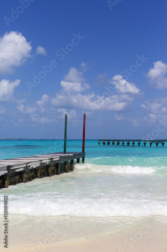 Colorful scenery on the beach. Long wooden piers with the turquoise water. Vertical wallpaper.