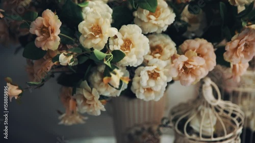 Flower bouqute in pink vase on table with present boxes and bird cage, photo studio decorations, close up photo