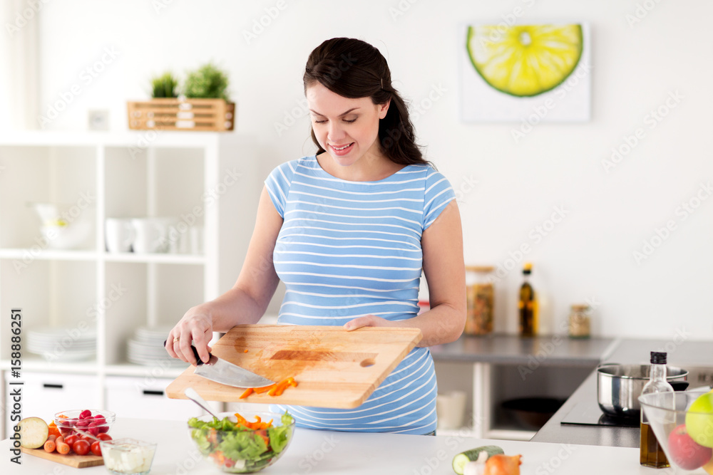 pregnant woman cooking vegetable salad at home