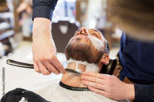 Photos man and barber with straight razor shaving beard