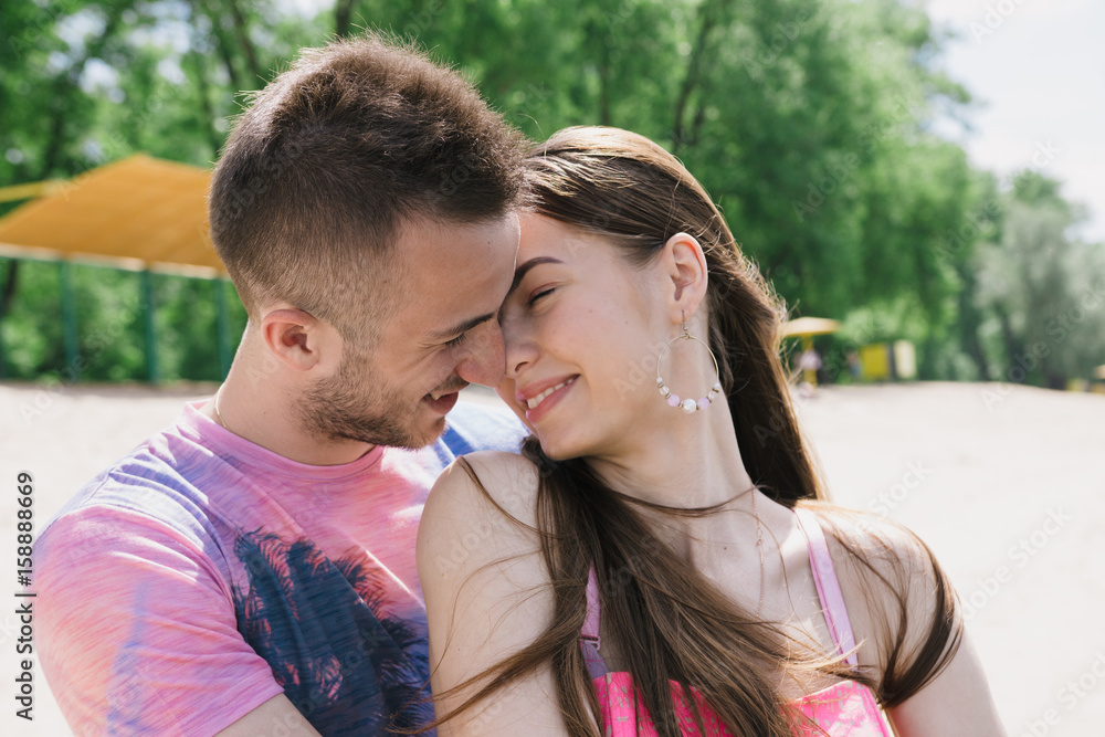 Young couple hugging and smiling at each other on the river bank. Walking along the sandy beach Young couple hugging and smiling at each other on the river bank. Walking along the sandy beach