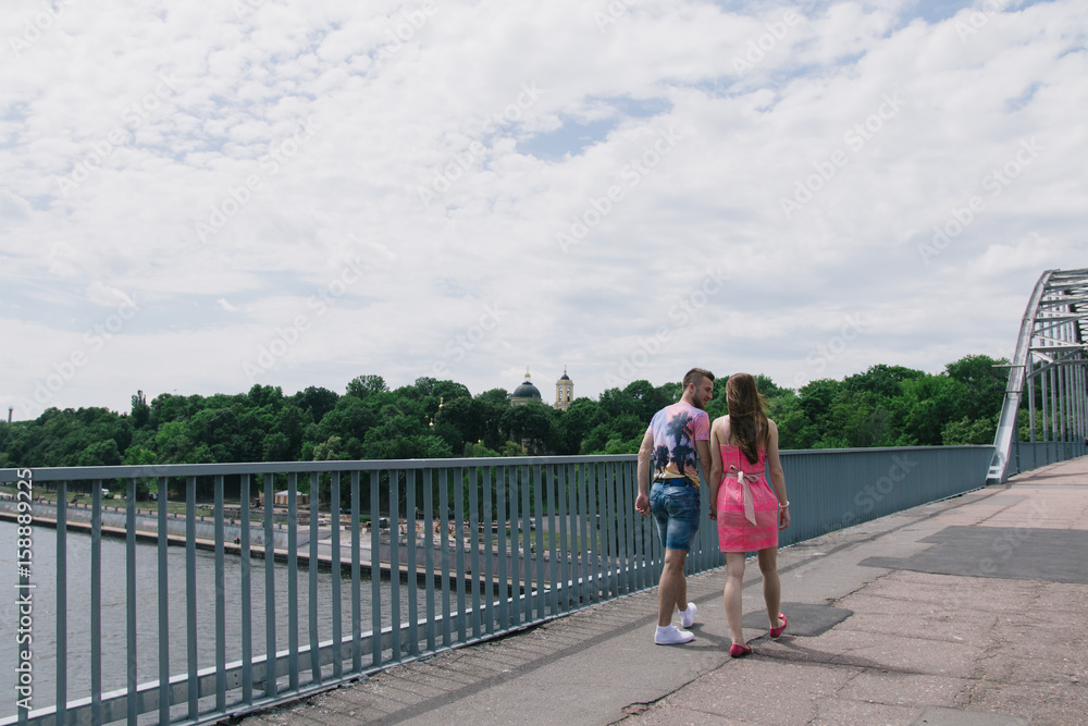 Young couple hugging and smiling each other walking on a bridge