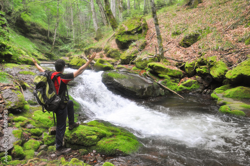 Man in nature. Hike with a backpack look at wild river. Happy hiker enjoy in wind mountain river