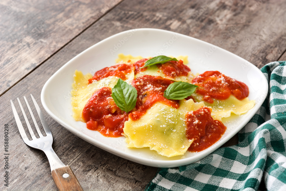 Ravioli with tomato sauce and basil on wooden background.
Ravioli with tomato sauce and basil on wooden background.