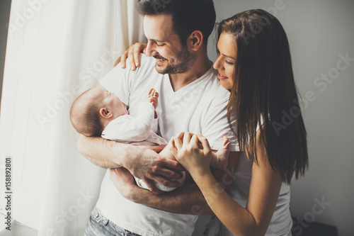 Happy family with newborn baby by the window photo