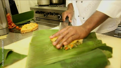 Cuban chef puts quiche in banana leaf, close up