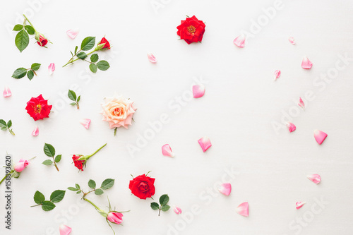 Flowers and petals background  made of pink and red roses  green leaves and pansy flowers on white background. Flat lay  top view