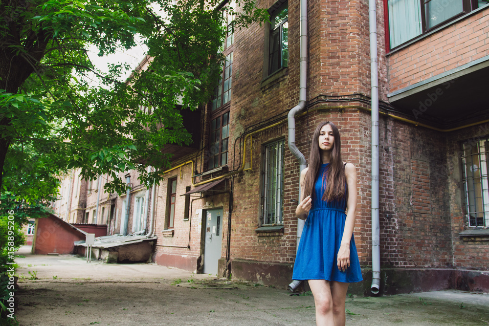 A very beautiful and cheerful girl stands on the street near a brick wall A very beautiful and cheerful girl stands on the street near a brick wall