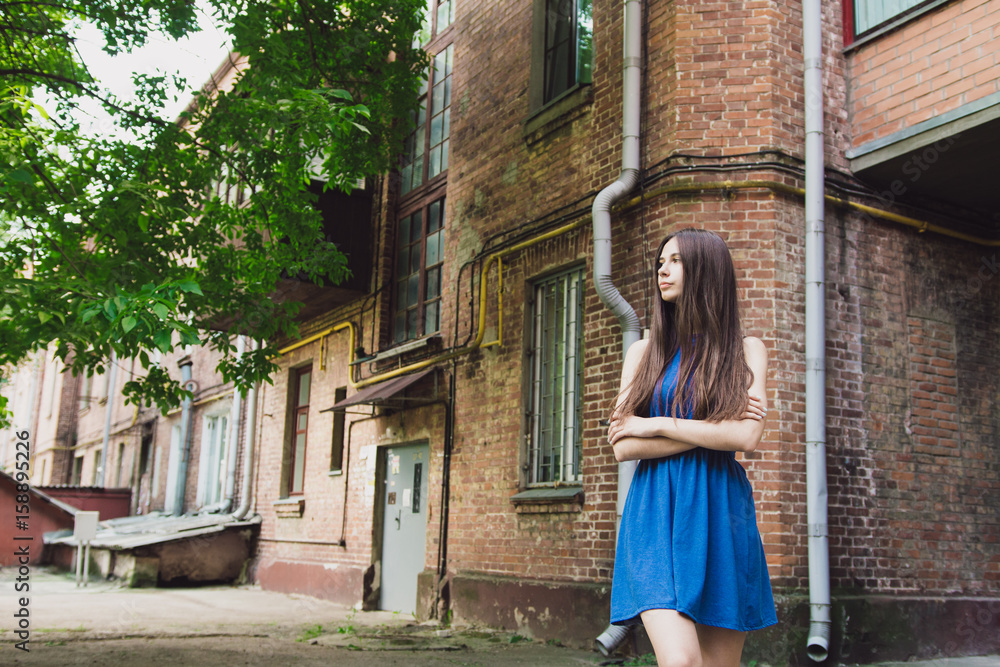 A very beautiful and cheerful girl stands on the street near a brick wall A very beautiful and cheerful girl stands on the street near a brick wall