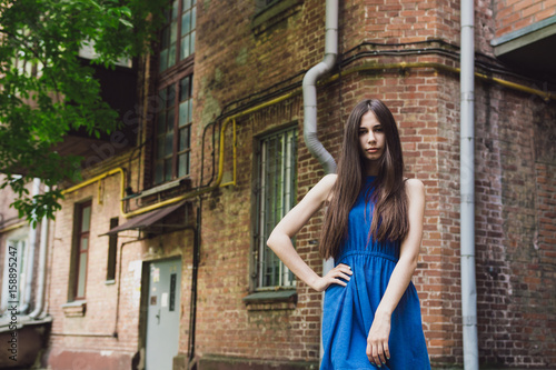 A very beautiful and cheerful girl stands on the street near a brick wall © combo1982