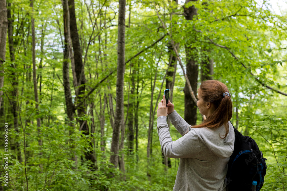 Young woman take a photo on her phone in the summer forest Young woman take a photo on her phone in the summer forest