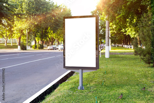 Blank white mock up of vertical light box in a bus stop in beautiful weather