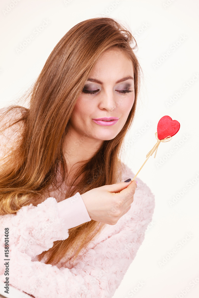 Flirty woman holding red wooden heart on stick Flirty woman holding red wooden heart on stick