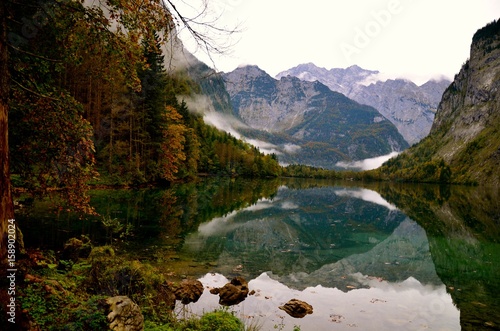 Autumn mountain's landscape with rocks, clouds and trees. Mirror reflection in the lake,