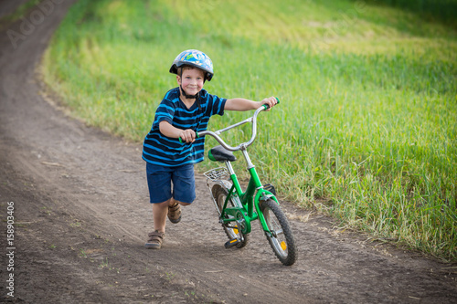 Fototapeta Naklejka Na Ścianę i Meble -  Little boy running with his bike on rural landscape