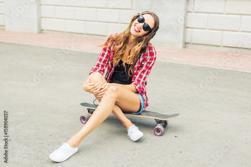 Beautiful and sexy girl sitting on the skateboard