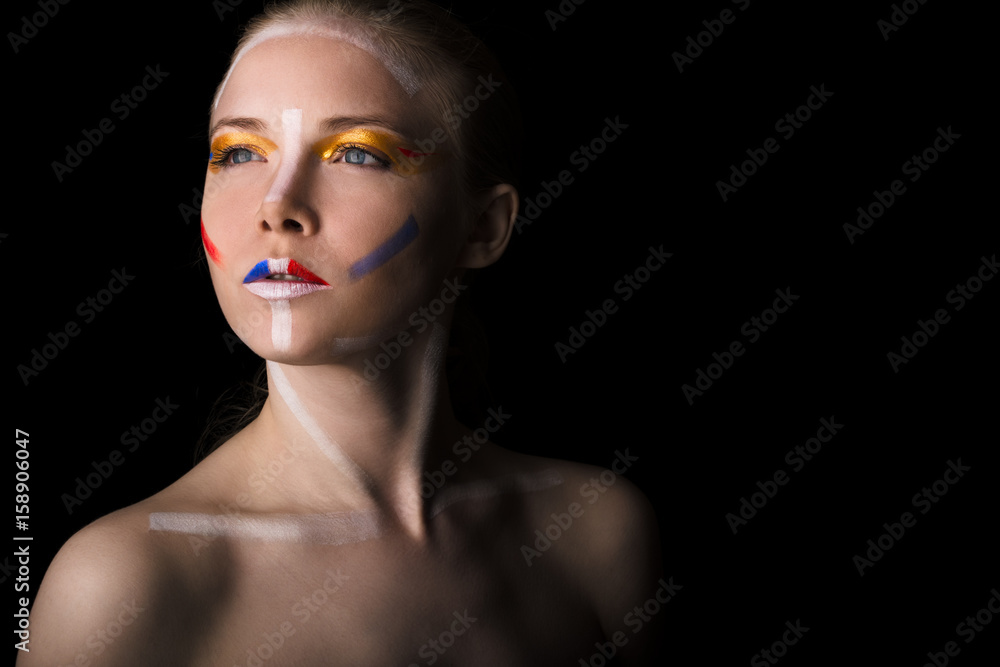 Naklejka premium Girl with colorful make-up. Portrait of a woman with colored make-up and naked shoulders on a black background close-up.