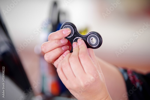 Young woman playing with a popular fidget spinner toy in her hands, on office background photo