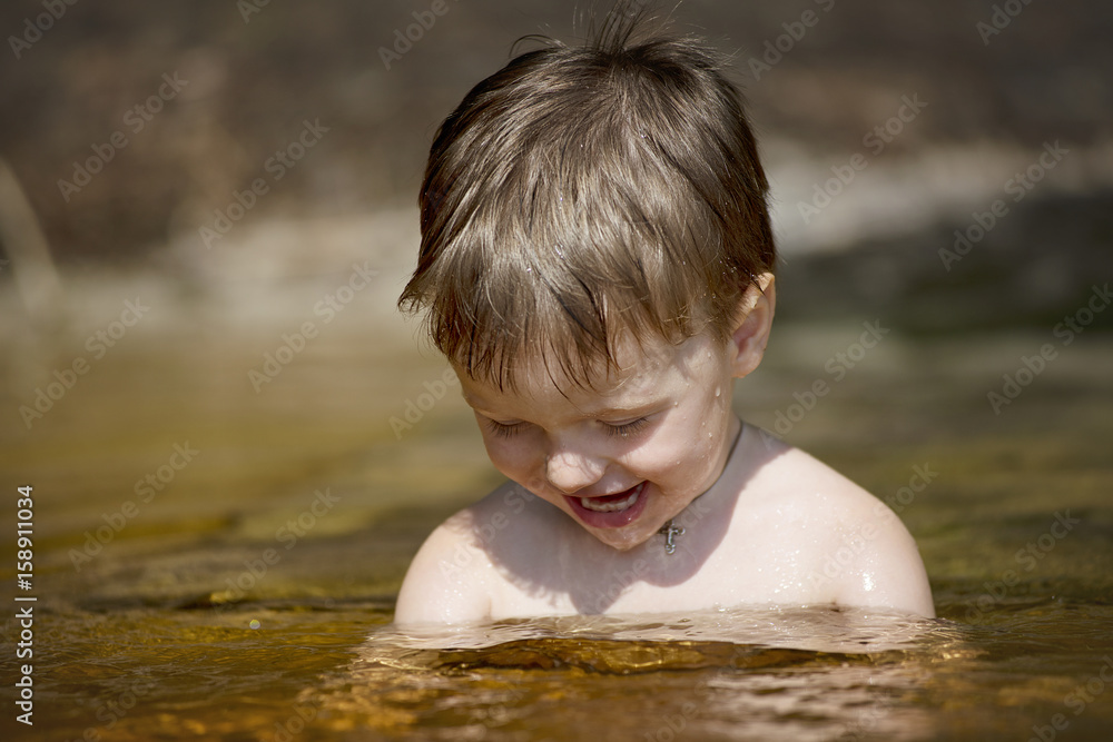 a little boy bathes in the lake and smiles a little boy bathes in the lake and smiles