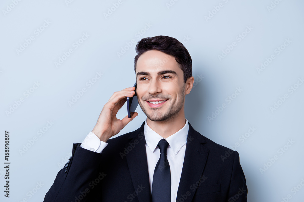 Successful and happy young brunete entrepreneur banker is having his phone nagotiations. He is in a suit and tie, standing isolated on pure background, smiling Successful and happy young brunete entrepreneur banker is having his phone nagotiations. He is in a suit and tie, standing isolated on pure background, smiling