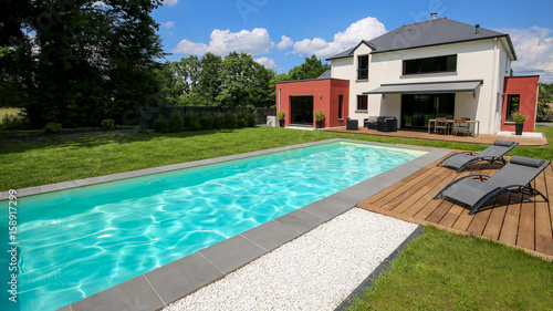 piscine avec terrasse dans jardin et maison moderne 1 photo