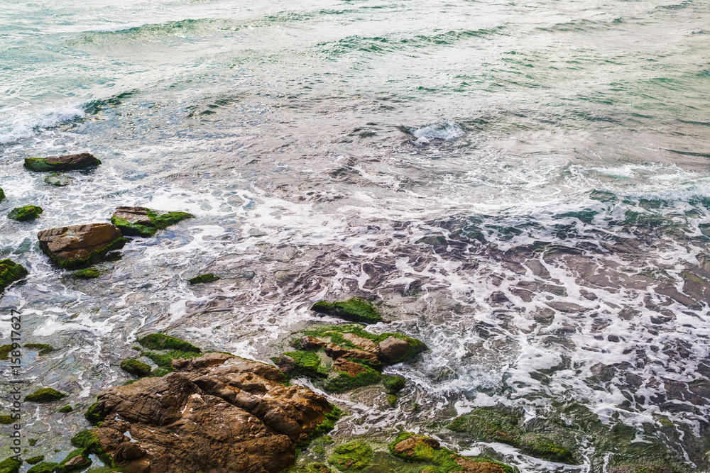 Sea surf and rocks covered with algae. Closeup of coastline. Sea surf and rocks covered with algae. Closeup of coastline.