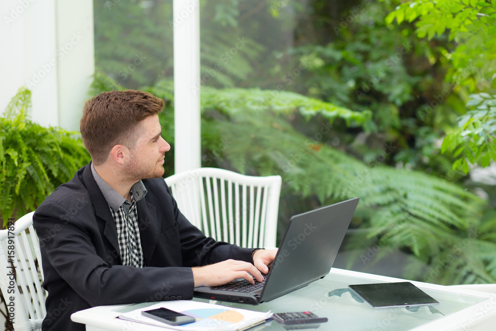 businessman and smiling, as he work on his laptop in the living room. businessman and smiling, as he work on his laptop in the living room.