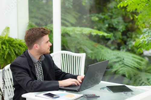 businessman and smiling, as he work on his laptop in the living room.