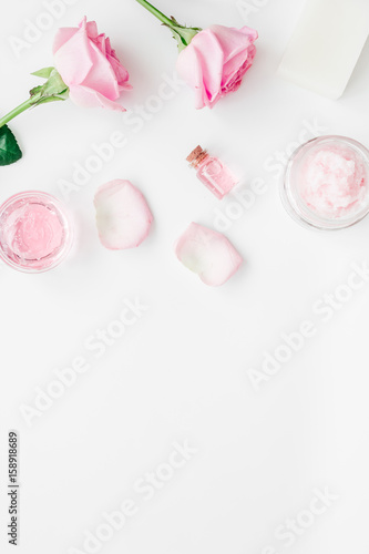 body treatment with rose flowers and cosmetic set white desk background top view space for text