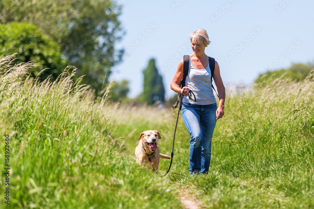 Obraz premium mature woman hiking with dog in the landscape