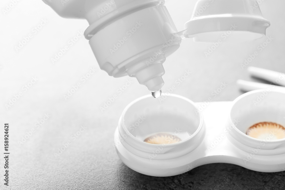 Bottle of solution and container with contact lenses on table Bottle of solution and container with contact lenses on table