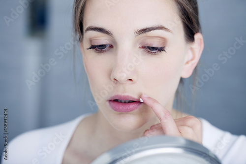 Woman applying cream to treat labial herpes photo