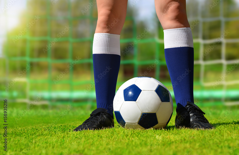 Feet of soccer player with ball on football field.