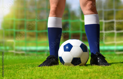 Feet of soccer player with ball on football field.