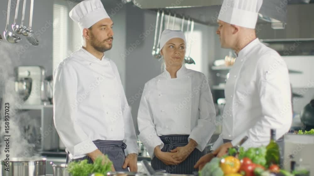 In the Modern Kitchen Team of Cooks Have Discussion. Kitchen is Full of Food Ingredients, Vegetables, Meat, Boiling Soup. Shot on RED EPIC-W 8K Helium Cinema Camera. In the Modern Kitchen Team of Cooks Have Discussion. Kitchen is Full of Food Ingredients, Vegetables, Meat, Boiling Soup. Shot on RED EPIC-W 8K Helium Cinema Camera.