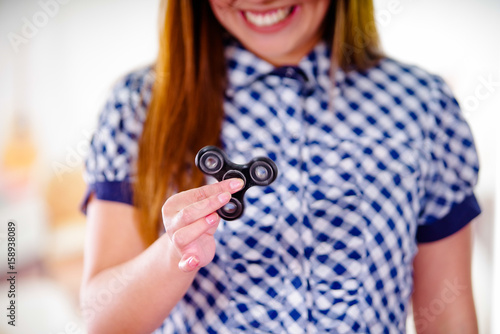 Young smiling woman holding a popular fidget spinner toy in her hand photo