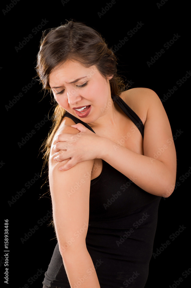 Beautiful young woman suffer from shoulder pain in a black background Beautiful young woman suffer from shoulder pain in a black background