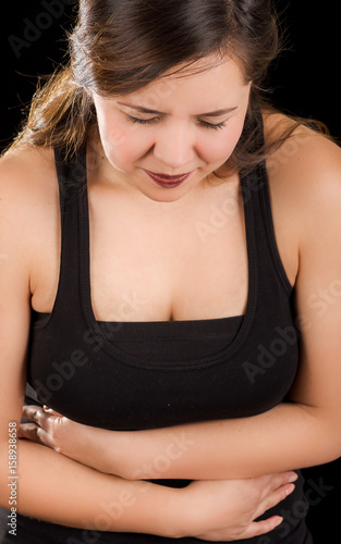 Beautiful young woman with stomach ache or nausea in a black background photo