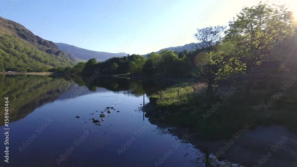 Low aerial background shot over a shallow lake and treelined bathed in sunshine. Low aerial background shot over a shallow lake and treelined bathed in sunshine.