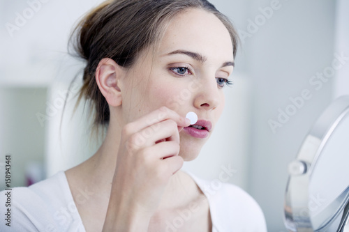 Woman applying a patch to treat labial herpes photo