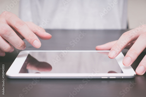 Close up of Male hands using tablet on the table.